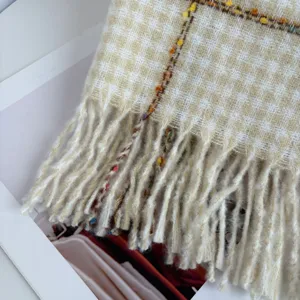 Close-up detail shot of a classic houndstooth warm winter scarf featuring soft fringe edges.