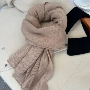 Primo piano di dettaglio di una sciarpa invernale in maglia kaki morbida con trama fine.