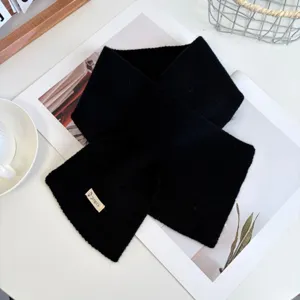 Close up detail of a cozy black knitted cross scarf winter warm neck wrap fashion accessory.