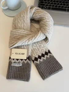 Detailed view of cozy cable knit winter scarf in beige with grey ribbed ends and pattern.