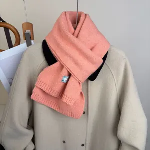 Primo piano dettagliato della morbida sciarpa in maglia rosa sopra un capo, tessuto caldo.