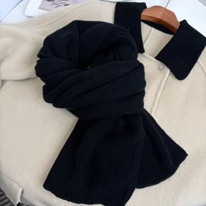 Dettaglio in primo piano di sciarpa in maglia nera, morbida e calda per la stagione invernale.