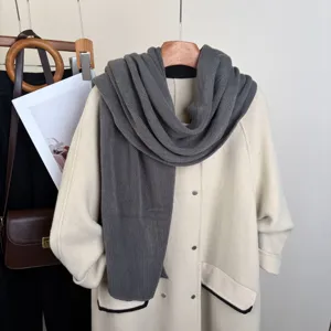 Dettaglio sciarpa in maglia grigio scuro con texture morbida e calore invernale.