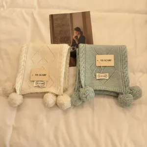 Detailed view of cozy knit pom-pom scarf in pastel colors, soft texture close-up shot.