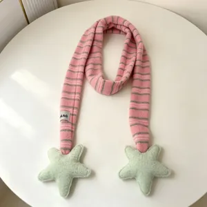 Pink striped plush scarf detail with cute green star ends, soft winter accessory close-up.