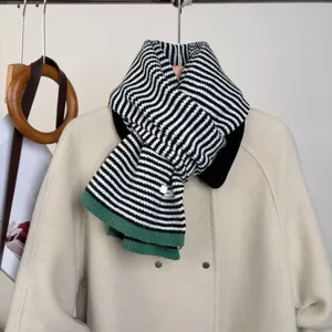 Classic black and white striped knitted scarf with green hem, cozy winter neck warmer.