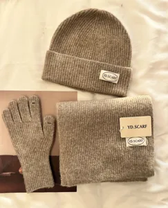 Detail shot of winter knitted hat scarf and gloves set in cozy beige warm fleece fabric style.