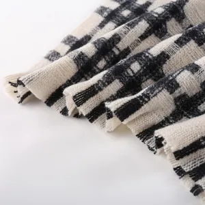 Close-up detail of black and white plaid scarf fabric, showing soft texture and cozy knit.