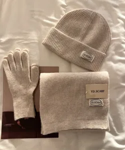 Cozy beige knit beanie, scarf and gloves set detail shot, warm winter accessory close up.