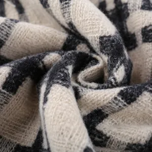 Close-up detail of soft black and white grid knit scarf fabric, showing cozy thick texture.