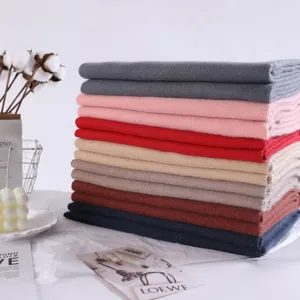Close-up detail of neatly stacked multi-color cashmere feel winter scarves on display.