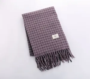 Detailed close-up view of a stylish purple plaid winter scarf with fringe and brand logo label.
