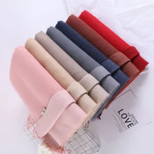 Detailed shot of stacked solid winter scarves in multiple colors, soft faux cashmere texture.