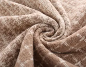 Detailed close-up of the soft textured plaid scarf fabric, showing fine wool-blend weaving.
