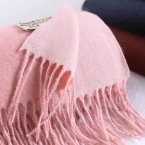Close-up view of a soft pink winter cashmere-like scarf showing delicate fringes and fine texture.
