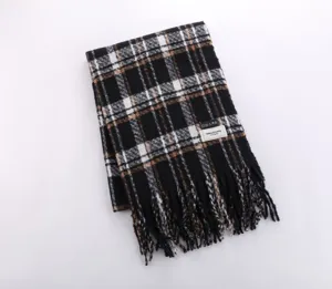 Close-up detail of the cozy black and brown plaid scarf featuring soft fringe and textured fabric.