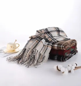 Detail view of stacked plaid imitation cashmere scarves with fringe and brand label.