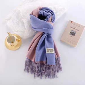 Detailed view of a thick double-sided imitation cashmere scarf with tassels and label.
