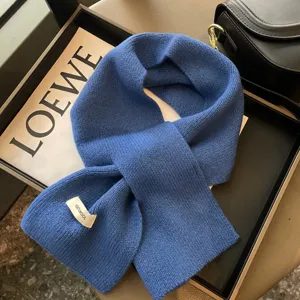Vista dettagliata della sciarpa incrociata in lana blu, morbida trama a maglia, scalda collo.