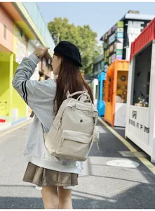 Detailansicht eines lässigen beigen Stoffrucksacks, getragen von einem Modell auf der Straße.