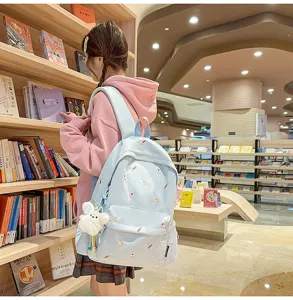 Detail view of light blue preppy backpack with sweet dessert embroidery in bookstore.