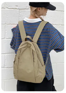 Casual backpack detail shot showing solid color fabric, dual shoulder straps and zipper.