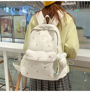 Casual canvas backpack detail shot, cute dessert embroidery and fluffy bear pendant.