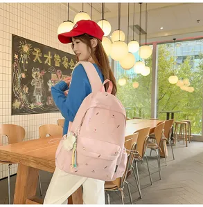 Pink canvas backpack for women, casual school bookbag with cute embroidery and pendant charm.