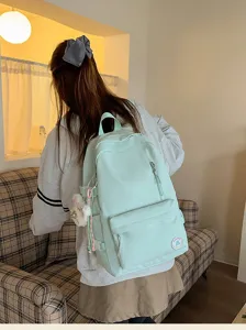 Detail view of a light green candy color school backpack worn by a student indoors.
