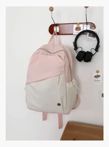 Vista dettagliata dello zaino casual rosa e bianco appeso a una parete chiara.