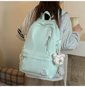Mint green casual canvas school backpack with front pocket and cute plush bear pendant.