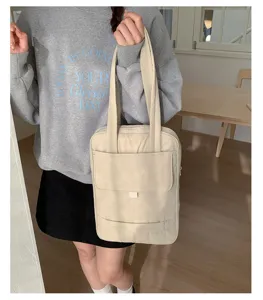Vista dettagliata della borsa tote minimalista beige con scomparti e tasche multiple.