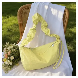Detail view of a stylish yellow pleated nylon crossbody bag, large capacity casual hobo design.