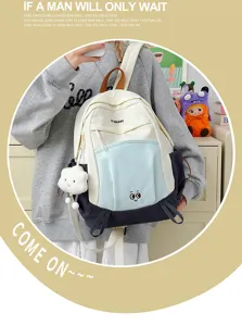 Color-blocked student backpack detail view, featuring front pocket and cute cloud pendant.