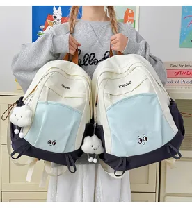 Large capacity color-blocked school backpack with cute cloud pendant for students.