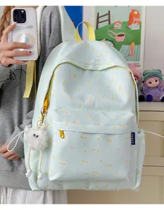 Detailed view of light green student backpack with yellow star print and cute plush pendant.