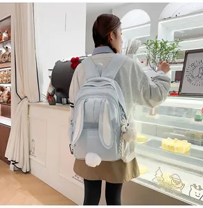 Cute bunny ear backpack detail shot, light blue school bag with fluffy tail and sweet bakery scene.