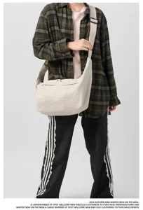 Detail shot of casual large capacity crossbody bag in beige, showing slouchy design and strap.