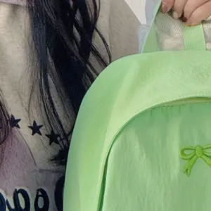 Close-up detail of the light green casual daily backpack featuring a cute bow decoration.