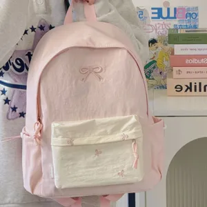 Cute pink canvas school backpack for teenage girls with bow embroidery and cream front pocket.