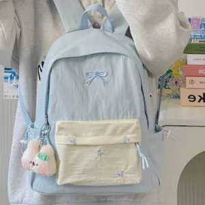 Detailed view of light blue school backpack with cute bow embroidery and plush bunny pendant.