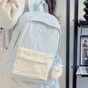 Detailed view of light blue school backpack with cute bow embroidery and plush charm pendant.