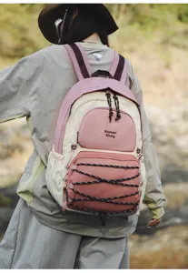 Detail view of a stylish pink and beige outdoor backpack with multi-pockets and cord.