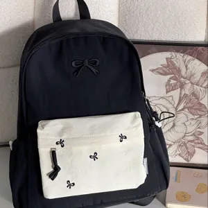 Close-up detail view of Japanese style preppy black backpack with cute bow embroidery and pocket.