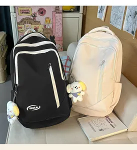 Detailed view of large capacity school backpacks in black and white with cute plush pendants.