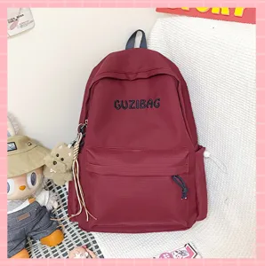 Detailed view of the Japanese ins style maroon backpack with cute pendant and front pocket design.