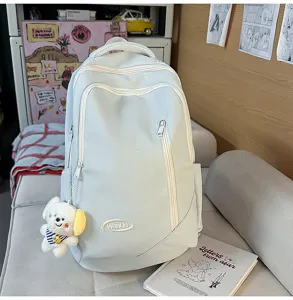 Detailed view of light blue large capacity backpack with multiple zipper pockets and cute dog pendant.