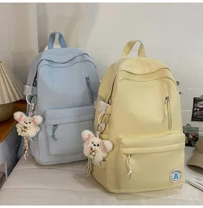 Detailed view of candy color school backpacks in blue and yellow with cute bear charms.
