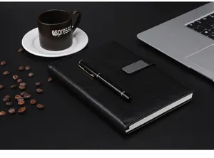 Detailed view of black A5 leather notebook with business pen, elegant office desk setup.