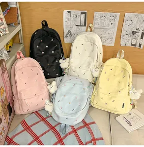 Korean style casual canvas school backpack for women with cute embroidery details and plush pendant detail